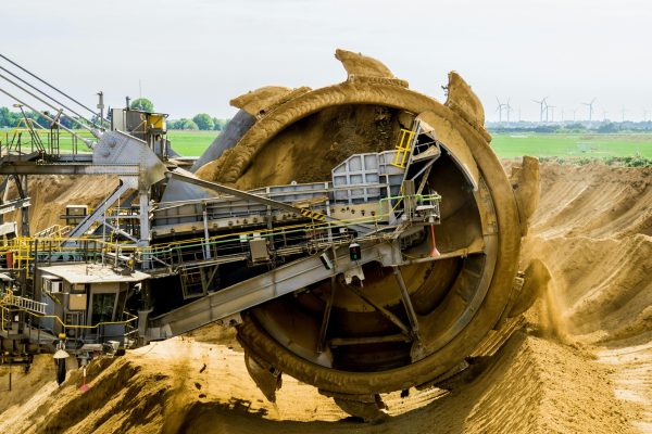 paddle-wheel-bucket-wheel-excavators-brown-coal-open-pit-mining-33192 A large bucket wheel excavator working in an open pit mine against a green landscape.